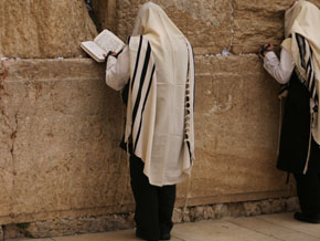 (Luk 8:44) Bild på en man som ber vid Västra muren i Jerusalem iklädd en bönesjal, tallit, med fyra hörntofsar. 